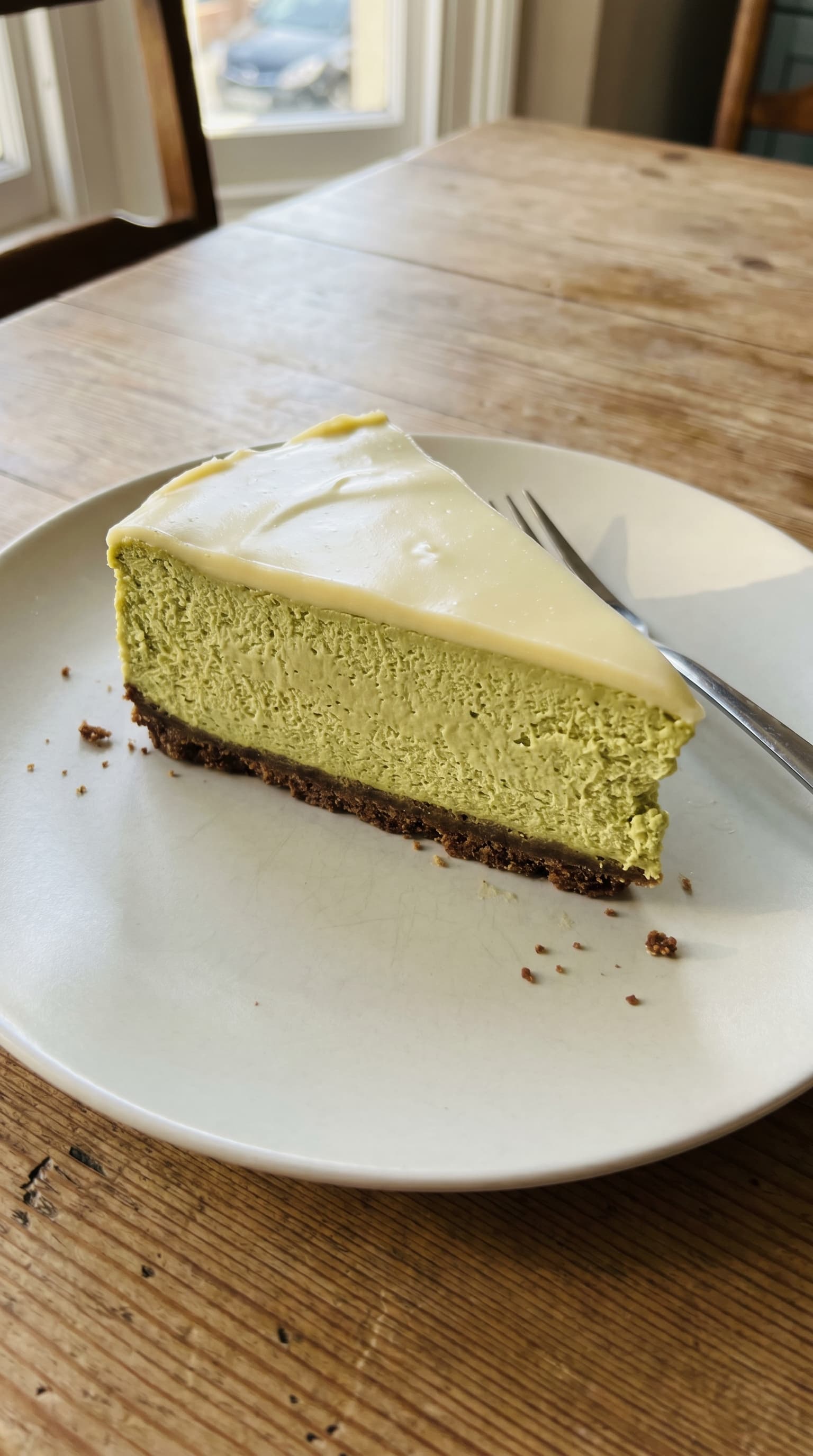 A creamy matcha white chocolate cheesecake slice served on a plate.